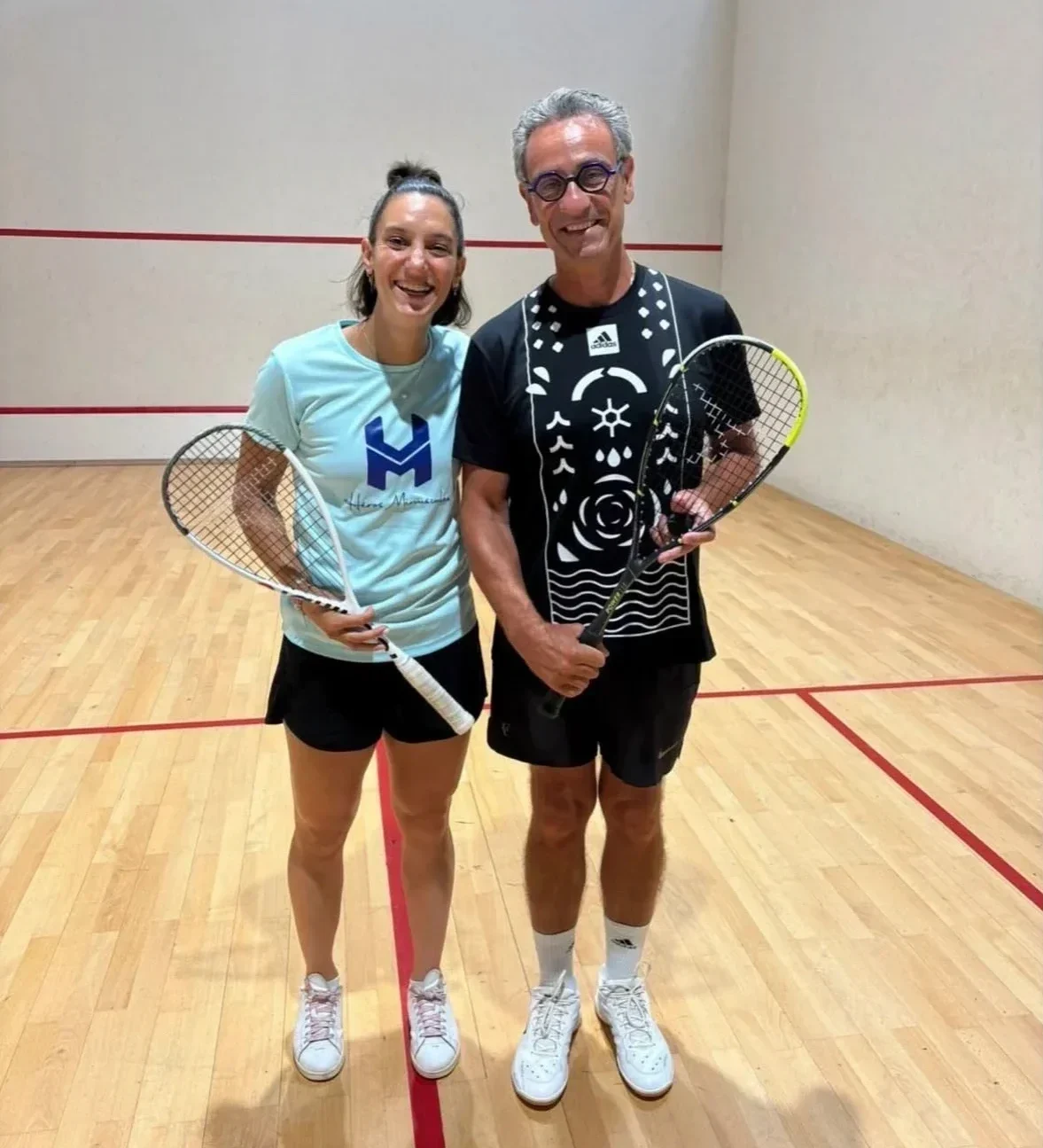 Deux joueurs de squash posant sur un terrain après un match amical.