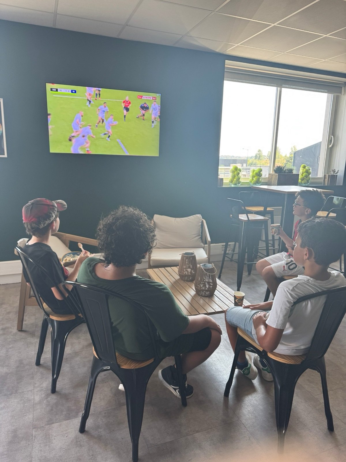 Enfants qui regardent un match à la télé du club house