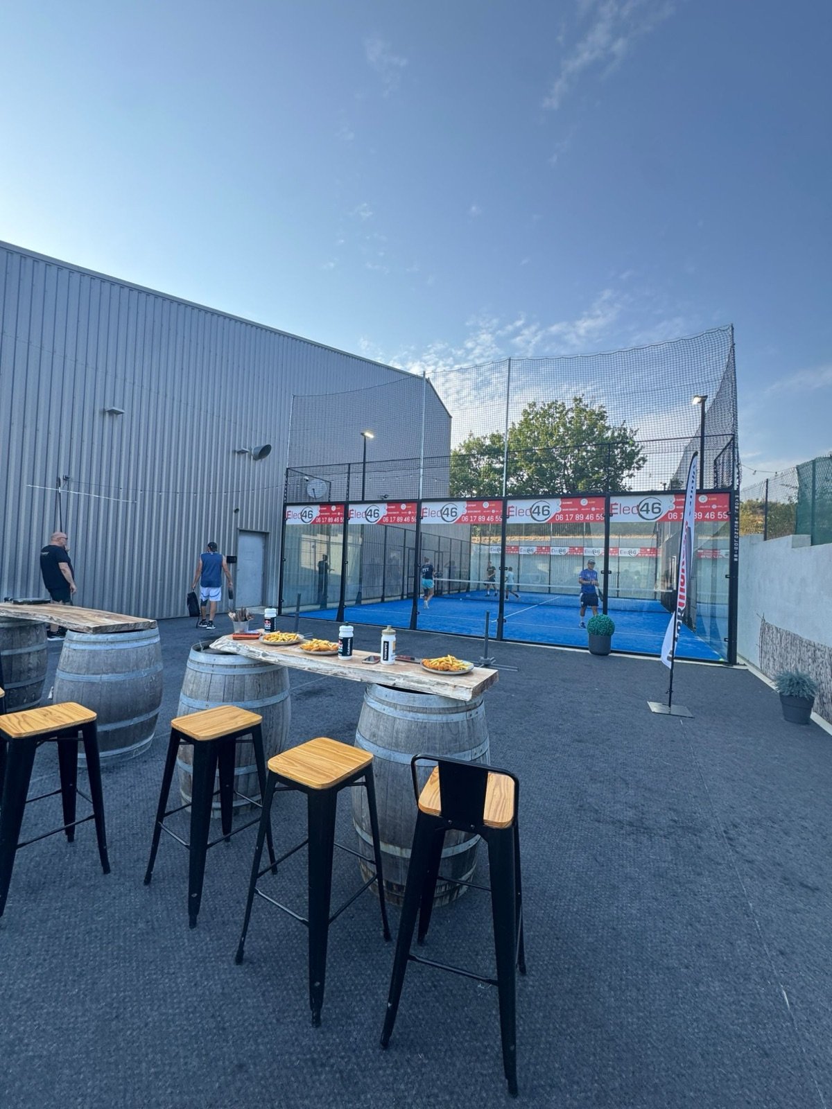 Terrasse avec tables en tonneaux devant le terrain extérieur